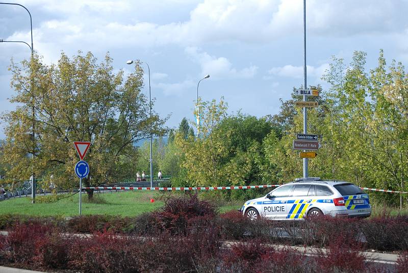 Policie hlídá u pásky naproti zimnímu stadionu, aby si chodci po trávě nekrátili cestu na most přes zábradlí.