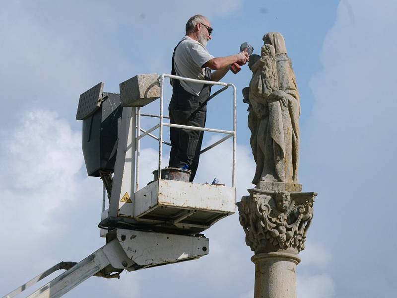 Restaurátor opravuje sochu sv. Anny Samotřetí na barokním sloupu na 1. náměstí v Mostě 