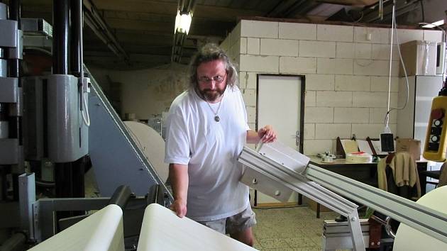 Marek Bajer u svého speciálně sestaveného stroje na výrobu materiálů pro zpevnění vazeb knih. 