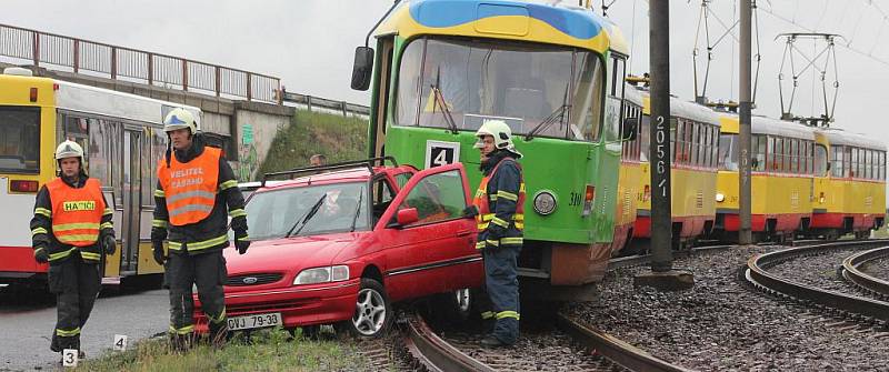 Hasiči vyprošťují havarovaného forda z kolejiště.