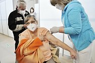 Zdravotní sestra Martina Kratochvílová očkuje Růženu Cífkovou ve velkokapacitním očkovacím centru v tělocvičně Sportovní haly v Mostě.