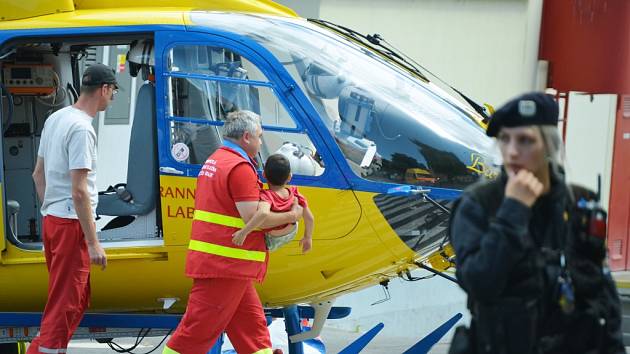 Záchranář nese přiotráveného chlapce u helikoptéry. 