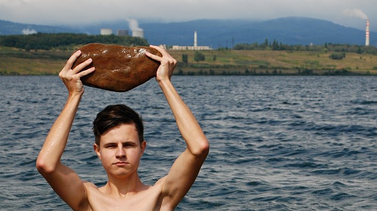Sedmnáctiletý Vojtěch ukazuje, jak velké jsou kameny metr od břehu jezera Most.