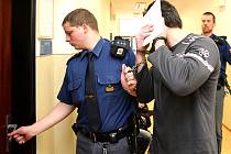 Justiční stráž vede obžalovaného Oldřicha Běhunka do soudní síně. Fotografem Deníku byl nepříjemně překvapen. Okamžitě si začal skrývat tvář.