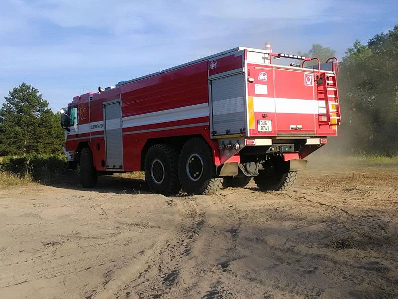 Hasiči likvidují požár uhelného prachu u rybníku v Komořanech