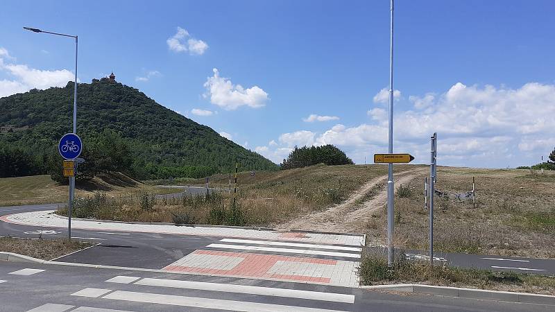 Cesta k dokončovanému altánu v městském ovocném sadu s výhledem na jezero Most, kostel a hrad Hněvín.