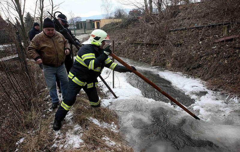 Dobrovolní hasiči a strážníci odstraňují ledové kry z potoka v Litvínově