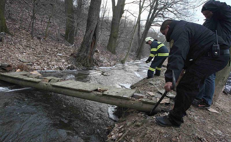 Dobrovolní hasiči a strážníci odstraňují ledové kry z potoka v Litvínově