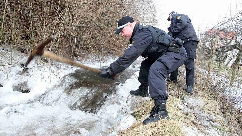 Dobrovolní hasiči a strážníci odstraňují ledové kry z potoka v Litvínově