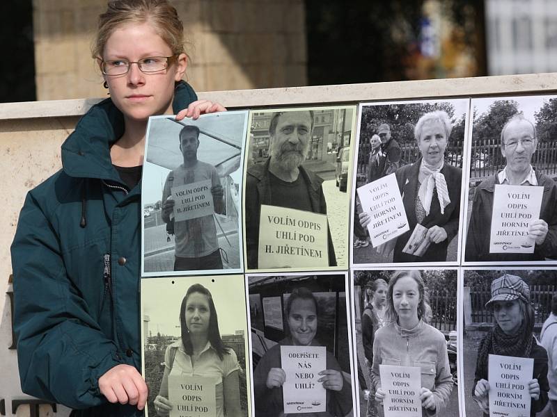 Aktivistka drží před mosteckým magistrátem fotografie lidí, kteří se účastní fotopetice proti těžbě uhlí pod Horním Jiřetíněm.