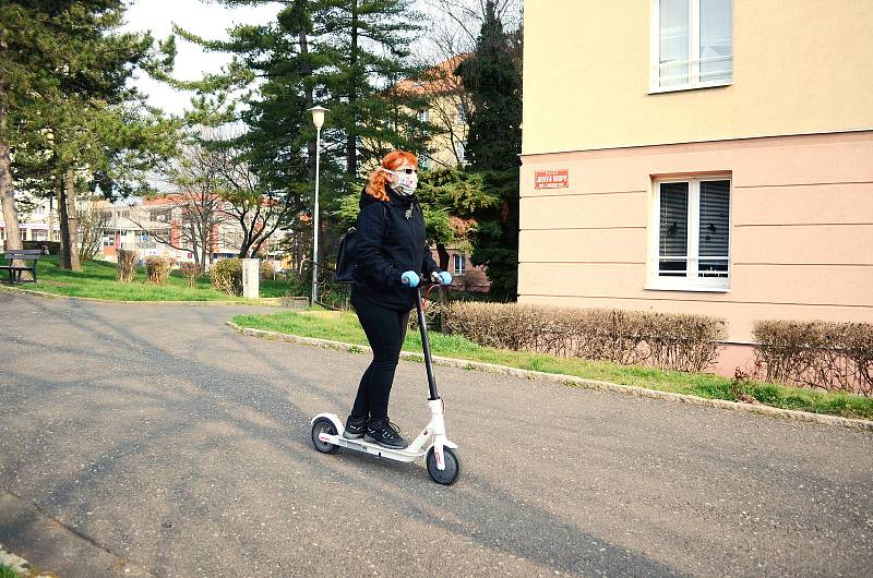 Kateřina Jermakovová rozváží v Mostě roušky na elektrokoloběžce.