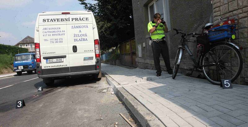 Dopravní policista fotografuje místo dopadu a bicykl zraněného muže