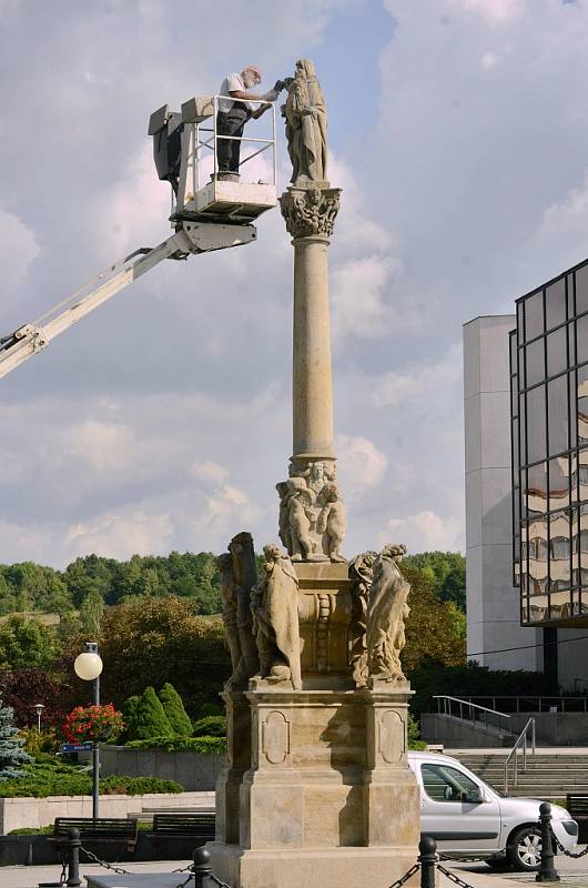 Restaurátor opravuje sochu sv. Anny Samotřetí na barokním sloupu na 1. náměstí v Mostě 