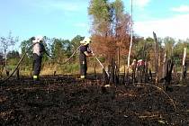 Hasiči likvidují požár uhelného prachu u rybníku v Komořanech