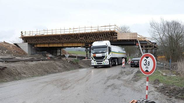 POD ROZPRACOVANÝM MOSTEM, klenoucím se nad silnicí na Puclice, projíždí kamion. Výška automobilů je tu omezena na 3,8 metrů.