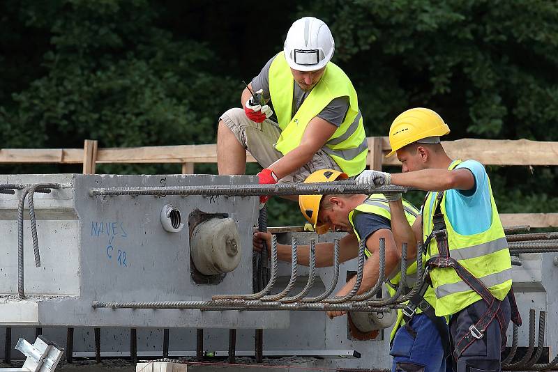 Největší kolový jeřáb v zemi v pondělí usadil na opravené pilíře deset betonových nosníků, z nichž se skládá nový most. Ten bude mít širší vozovku i vyšší nosnost. Řidiči se po něm projedou až příští rok.