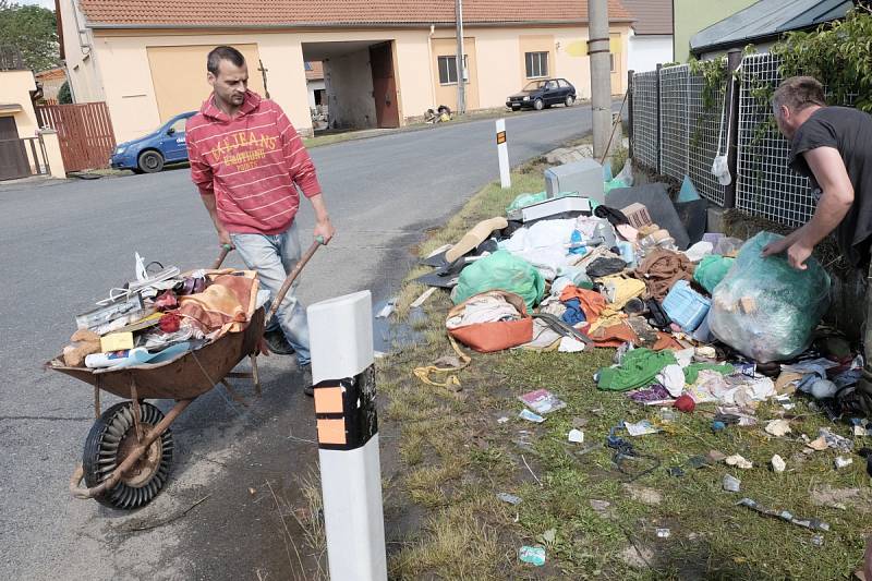 NA NÁVSI VE STRÝČKOVICÍCH pomáhají lidé před domem Marcely Kuchárikové odklízet téměř veškeré vybavení domu, které v noci ze soboty na neděli zničila povodeň.