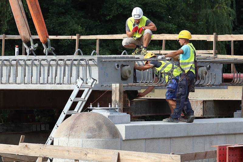 Největší kolový jeřáb v zemi v pondělí usadil na opravené pilíře deset betonových nosníků, z nichž se skládá nový most. Ten bude mít širší vozovku i vyšší nosnost. Řidiči se po něm projedou až příští rok.