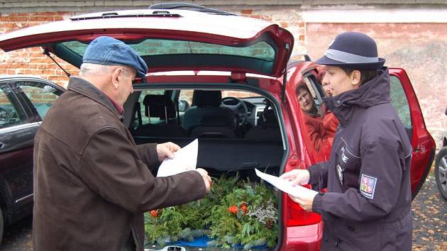 Policistka upozorňuje návštěvníka hřbitova na nebezpečí krádeže.