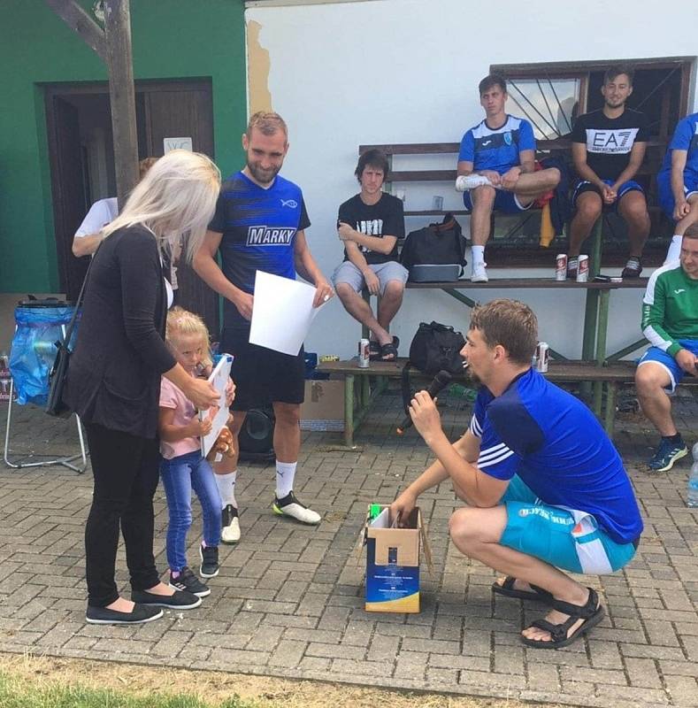 Martin Sladký (stojící) s Janem Zavadilem (vpravo v podřepu) předávají šek a hračky mamince malé Sofinky.