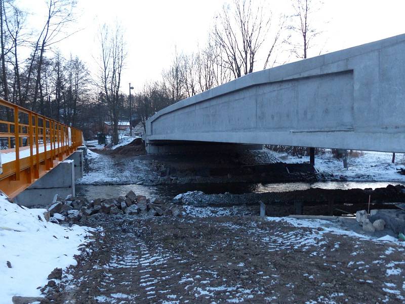 NOVÝ MOST VYROSTL na silnici č. 1973 v Tasnovicích. Měl být hotový v prosinci 2015, ale termín bylo nutné prodloužit. Rychlost je zde omezena na 30 km/h a chodci řeku zdolávají po provizorní lávce.