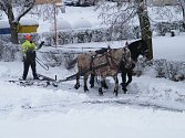 Prohrnování sněhu pluhem taženým koňmi.