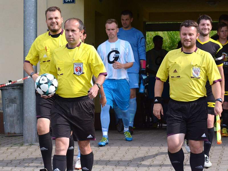 Jde se na věc... Trojice rozhodčích v čele s hlavním Otakarem Pešavou (s míčem) přivádí dva týmy na hrací plochu, kde se o chvíli později rozběhne jedno z mistrovských utkání.