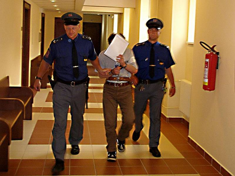Soud vyhověl přání obžalovaného Jiřího Homoly a nepovolil fotografofání v jednací síni. I v eskortě se Homola ukrýval.