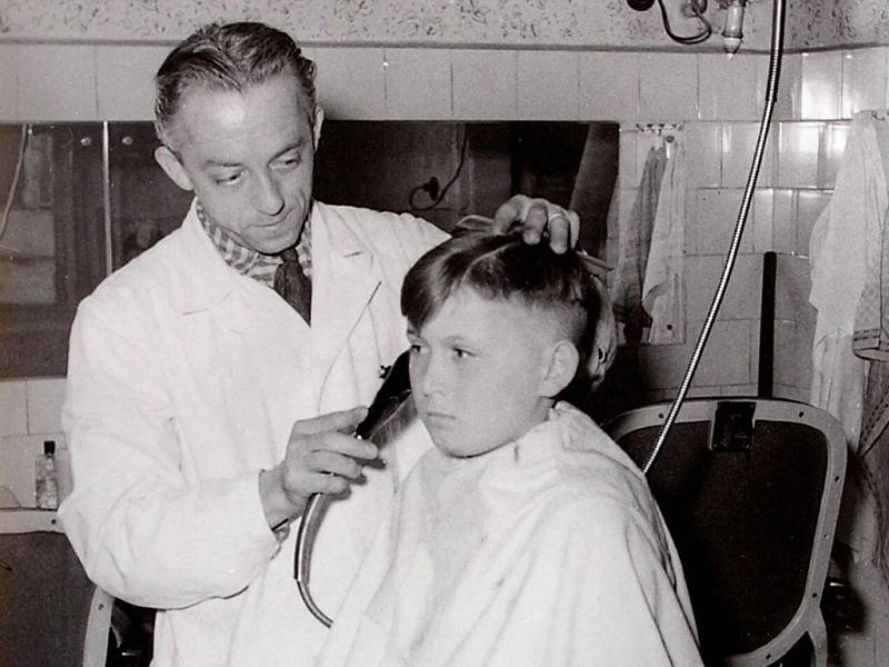 KDO JE ONEN MALÝ ZÁKAZNÍK? Na snímku z 50. let minulého století je  zvěčněný holič Antonín Novotný, kterak stříhá hocha. Víte, kdo by malý zákazník mohl být?