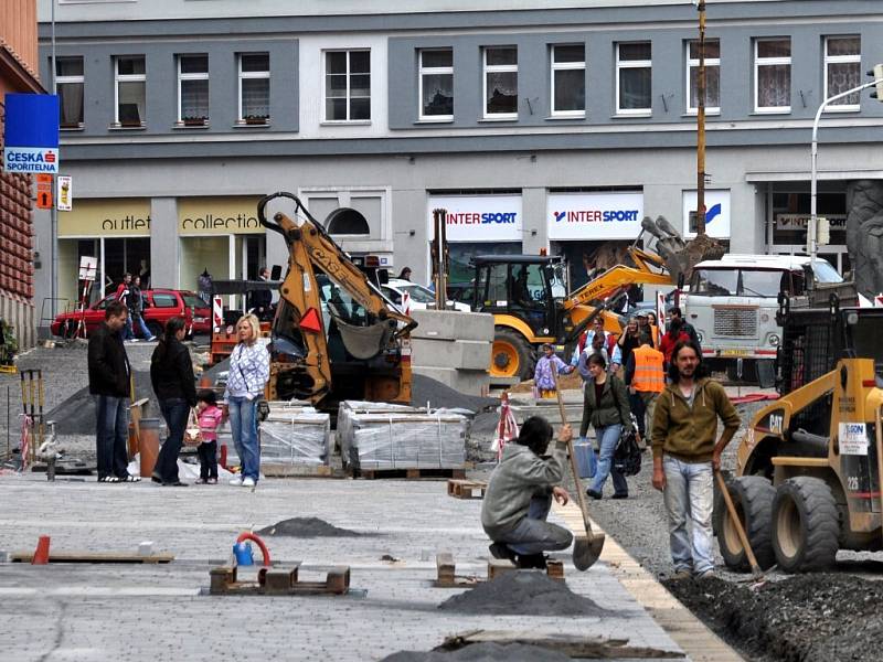 Rekonstrukce I. části pěší zóny v Chebu. Dlaždiči už položili část nové dlažby od křižovatky s Evropskou ulicí. Na portější straně likvidují stavební dělníci zasypané základy bývalých veřejných záchodků.