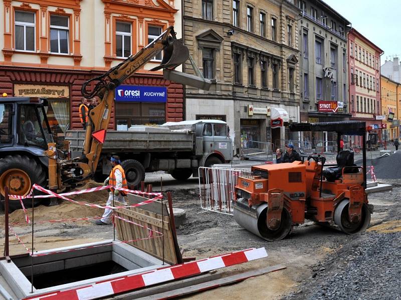 Rekonstrukce I. části pěší zóny v Chebu. Dlaždiči už položili část nové dlažby od křižovatky s Evropskou ulicí. Na portější straně likvidují stavební dělníci zasypané základy bývalých veřejných záchodků.