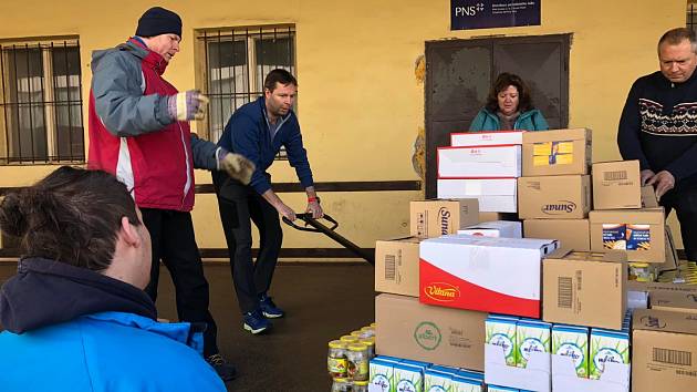 Několik dobrovolníků pomáhalo s tříděním a nakládáním věcí v potravinové bance.