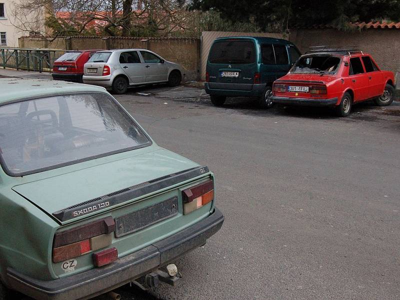 Dva vraky hyzdí starorolskou Nádražní ulici. Zelená Škodovka (v popředí) zmizí příští pondělí. Vyhořelý vůz s ústeckou značkou v pozadí na odtah teprve čeká.