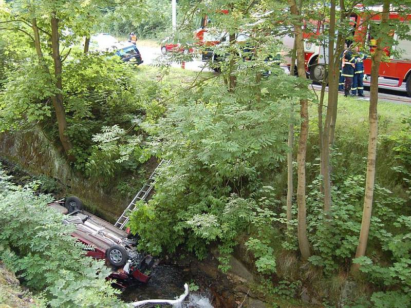 Srážka dvou automobilů v Jáchymově. Jeden z vozů po kolizi narazil do stromu, druhé auto se zřítilo do potoka.