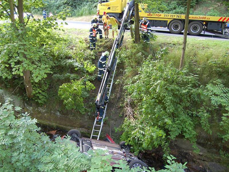 Srážka dvou automobilů v Jáchymově. Jeden z vozů po kolizi narazil do stromu, druhé auto se zřítilo do potoka.