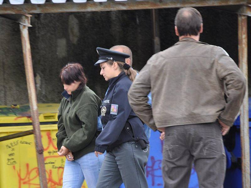 Ve středu 1. září prováděli policisté na sídlišti v Nejdku rekonstrukci pokusu o vraždu - otravu Fridexem. Láhev s Fridexem žena vyhodila do zeleného kontejneru. Žena obviněná z vraždy v tmavozelené bundě.