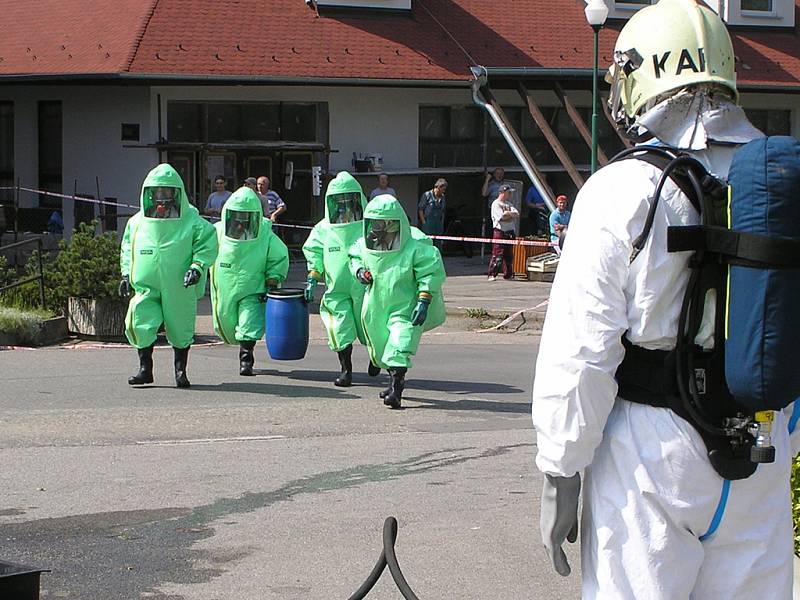 Hasiči přinášejí v barelu uloženou chemikálii, kterou zajistili ve škole.