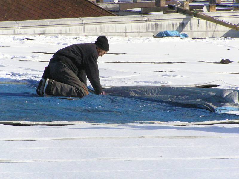 Řameslníci zakrývají střechu provizorně plachtou a následně budou dělat novou střechu