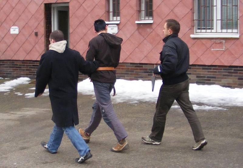 Eskorta jednoho z pachatelů do pražské cely předběžného zadržení. O vazbě se rozhodne ve čtvrtek 