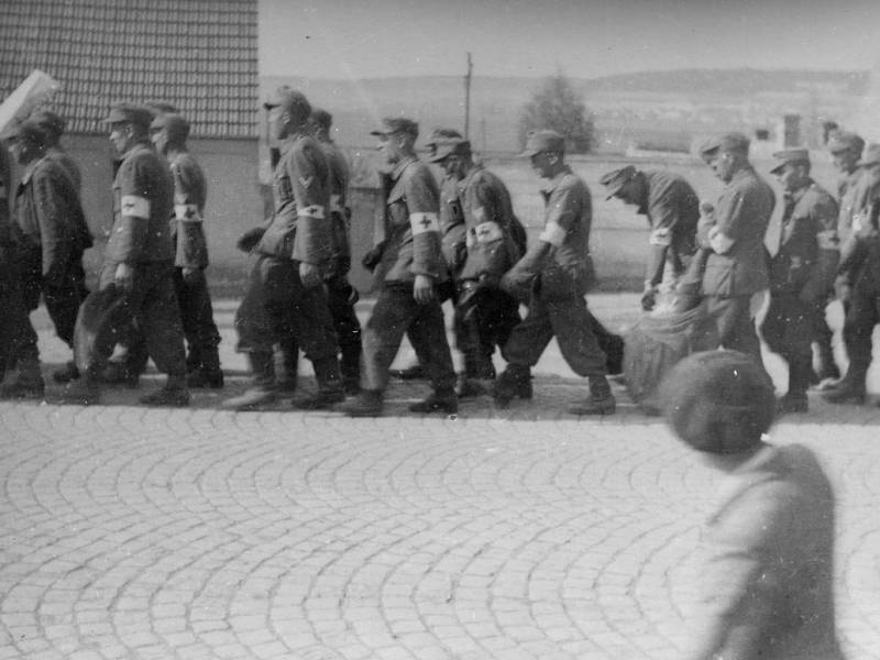 K západním spojencům ustupující kolona poražené a odzbrojené německé armády s sebou nese i své těžce zraněné a mrtvé. Snímek byl pořízen v květnu 1945 v Doksech na karlovarské silnici. 