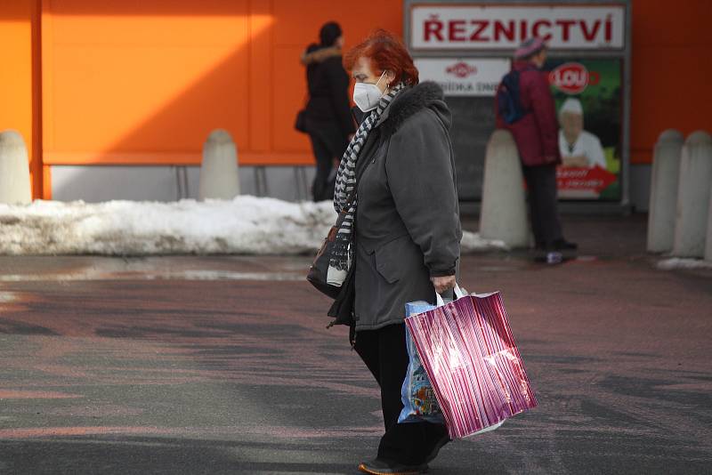 Do obchodů chodí většina lidí nyní s rouškami.