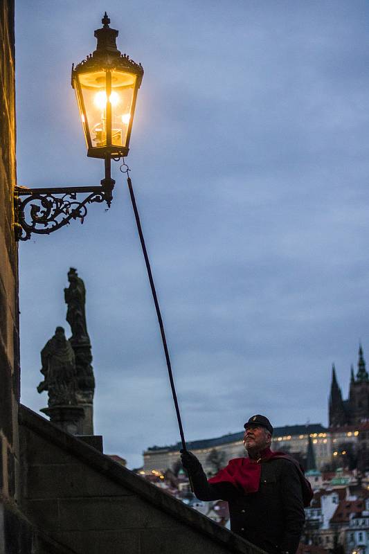 Lampář v centru Prahy při rozsvěcování plynových lamp.