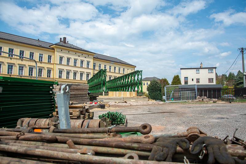 Dělníci připravují mostní provizorium přes říčku Čistou, po kterém budou jezdit auta během opravy památkově chráněného mostu v centru Hostinného.