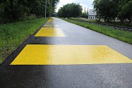Žluté vodorovné značení na cyklostezce podél říčky Vrchlice v Kutné Hoře.