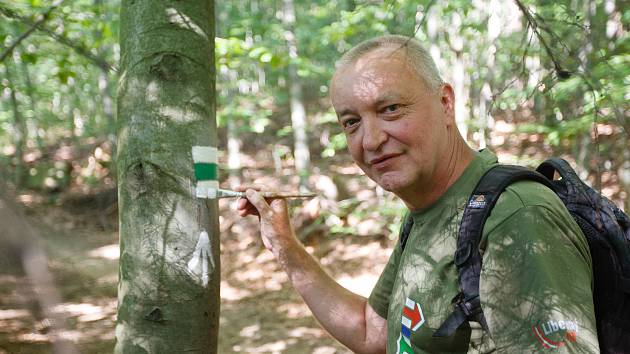Jaromír Růžička z Klubu českých turistů obnovuje turistickou značku na kmenu stromu.