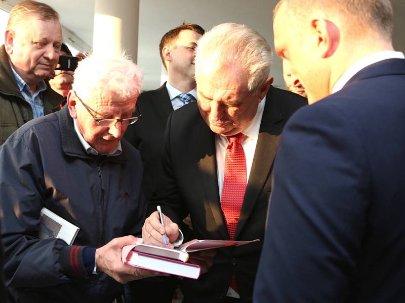 Miloš Zeman se podepisuje do památníčku svým fanouškům.