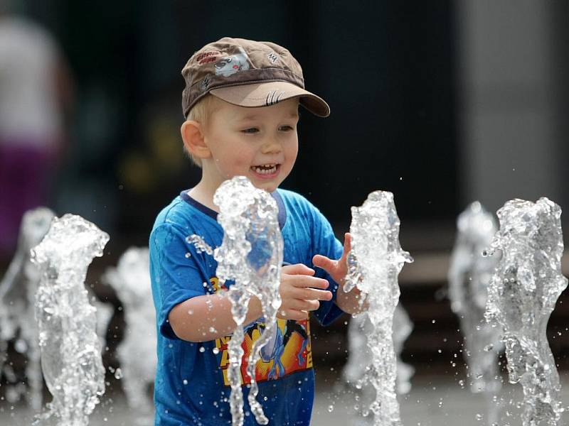 Děti se brouzdají přímo mezi vodotrysky před obchodním domem Plaza.