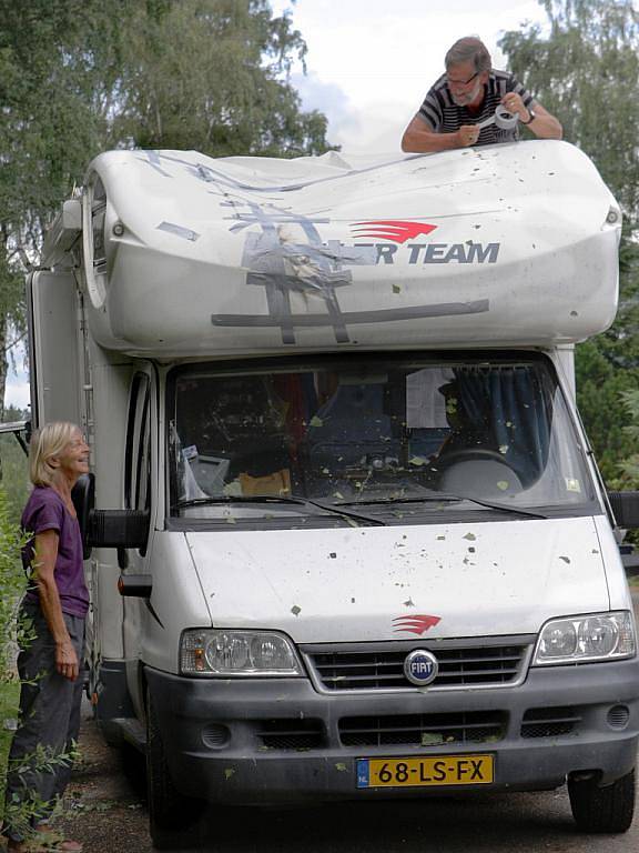 Holandský turista se snaží provizorně zalepit karavan, poničený padajícími větvemi po čtvrteční smršti. Autokemp Pavlovice v Liberci.