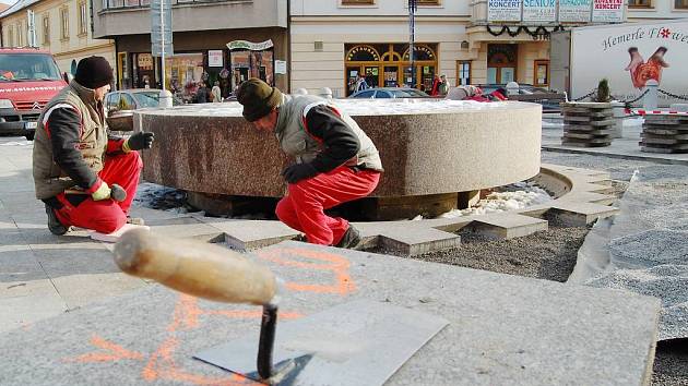 Pohled na rozebranou dlažbu okolo fontány na jindřichohradeckém Masarykově náměstí. Před zimou zde dělníci vyrovnávají povrch.  