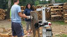 Jednou z mnoha činností v Podcestném mlýně je zpracování dřeva. Výtěžek z něj putuje zpět na podporu komunity. S obrovskými špalky zápasí i Katka.